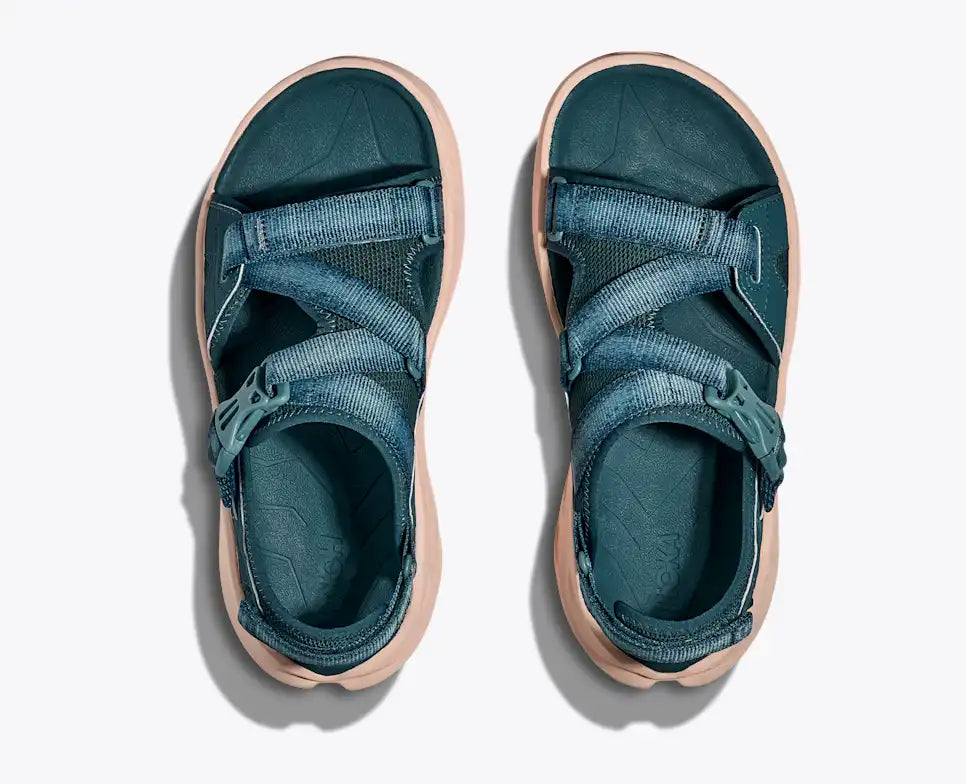 Pair of teal sandals with beige soles on a white background