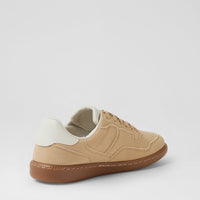 A low-top sneaker shown from a three-quarters rear angle, featuring a beige suede upper, a white heel tab, and a brown gum sole, set against a plain light gray background.