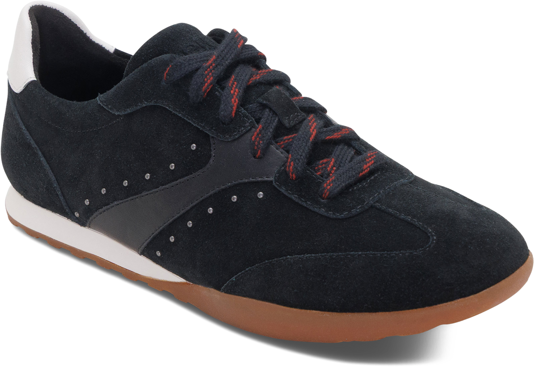 A low-top sneaker in black suede and synthetic leather, featuring black laces with red stripes, a white midsole, and a brown gum outsole, shown on a white background.