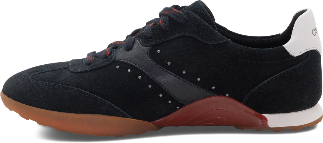 A black suede and synthetic leather sneaker with a translucent brown gum sole, a white heel tab, and red laces, shown from a side profile on a white background.